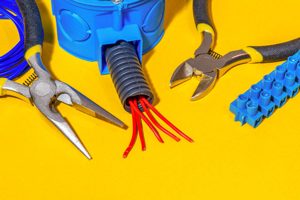 Peças sobressalentes, ferramentas e fios para substituição ou reparação de equipamento eléctrico sobre fundo amarelo
 - Foto, Imagem