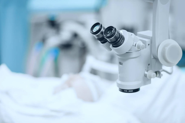 Il dottore esamina il fondo al microscopio, paziente sotto copertura sterile. Correzione visione laser lasik
 - Foto, immagini