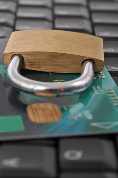 Bankbeveiligingsconcept met een hangslot op een bankkaart op een computertoetsenbord close-up - Foto, afbeelding