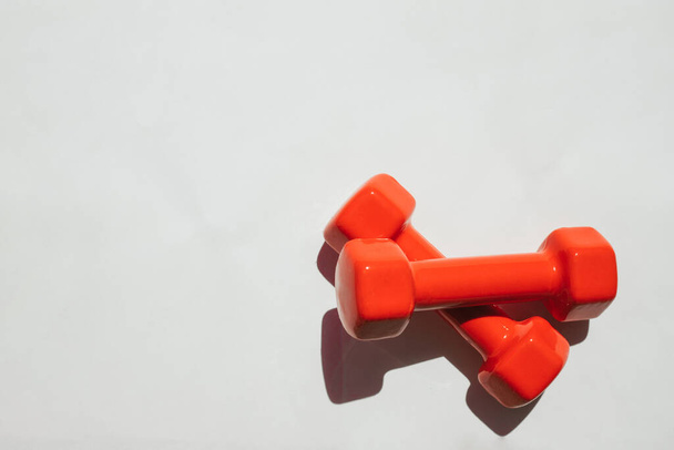 Red dumbbells for sports on a white background. Sports equipment for home sports. - Fotó, kép