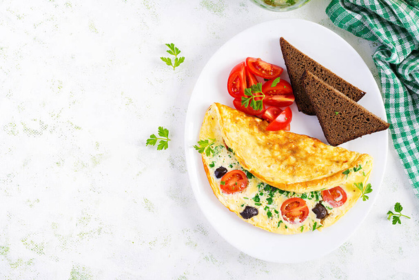 Pequeno-almoço. Omelete com tomates, azeitonas pretas, queijo cottage e ervas verdes na placa branca. Frittata - omeleta italiana. Vista superior
 - Foto, Imagem