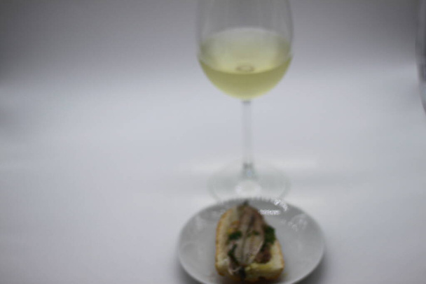 top van ansjovis en glas witte wijn - Foto, afbeelding