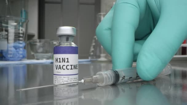 H1N1 vaccine vial in medical lab with syringe placed moving past them in macro view. - Filmmaterial, Video