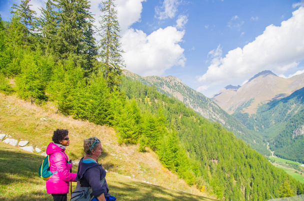 két fiatal női túrázók sétálni boldogan a hegyi utakon, és megcsodálják a kilátást a nyaralás alatt - Fotó, kép