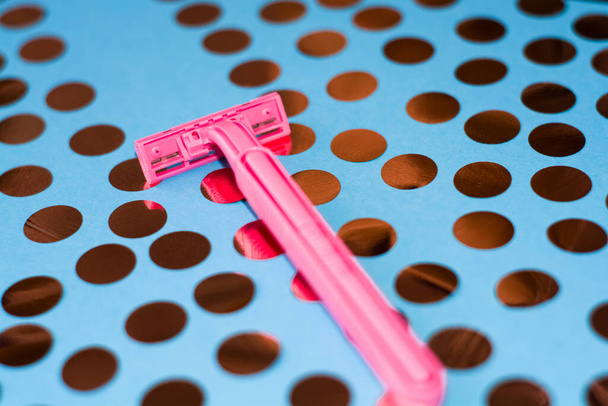 Fényes háttér konfettivel és rózsaszín női borotvával. Borotva a sima borotválkozáshoz. Éles borotva személyes higiéniai rutinhoz. - Fotó, kép
