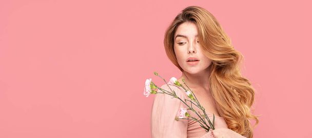 Beauty portrait of natural young redhead woman with meadow flowers. Girl with freckles on face posing on pastel pink background. - Photo, Image