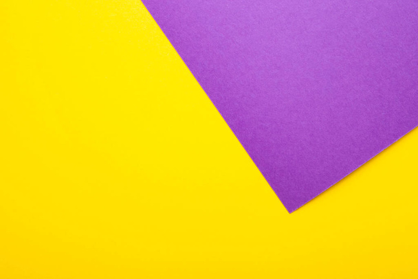 Μωβ και κίτρινο χαρτί ως φόντο. Δίχρωμο φωτεινό χαρτί υφή, κορυφαία προβολή με θέση για κείμενο - Φωτογραφία, εικόνα