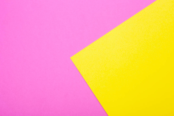 Roze en geel papier als achtergrond. Twee gekleurde heldere papieren textuur, bovenaanzicht met plaats voor tekst - Foto, afbeelding