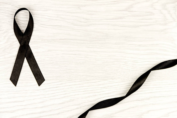 Oncologische ziekte concept. Een zwart lint als symbool van melanoom geïsoleerd op lichte houten achtergrond - Foto, afbeelding