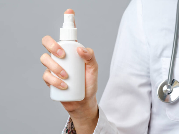 Doctor holding a bottle of alcohol spray. Doctor recommend to use antiseptic gel. Isolated on gray - Fotó, kép