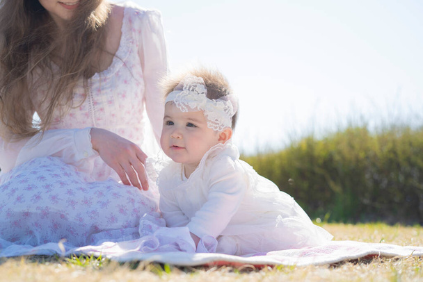 Parkta Corolla giyen beyaz bir anne ve bebek oynuyor. - Fotoğraf, Görsel