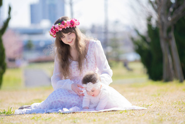 Joven madre caucásica y bebé con corola jugando en el parque
 - Foto, Imagen