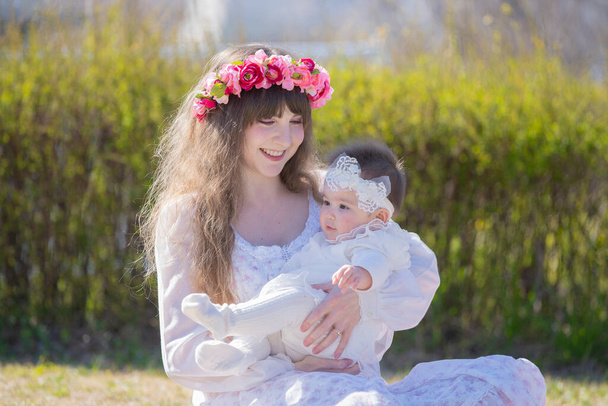 Joven madre caucásica y bebé con corola jugando en el parque
 - Foto, Imagen