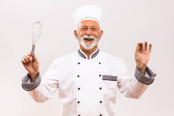 Image of  musical conductor senior chef with wire whisk on gray background. - Valokuva, kuva