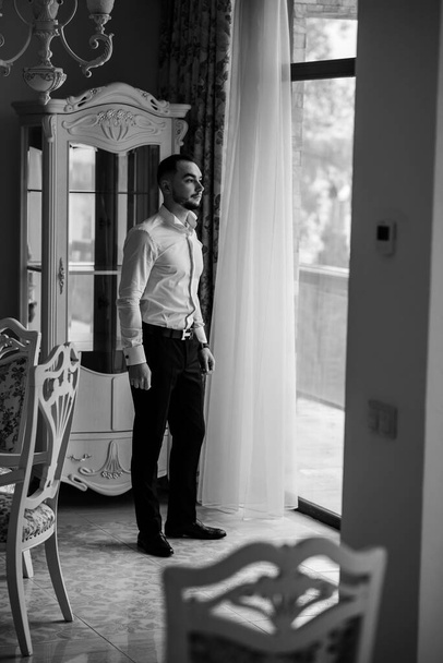 Respectable young man standing in a room with classic interior. Luxury. Men's beauty, fashion. - Fotografie, Obrázek