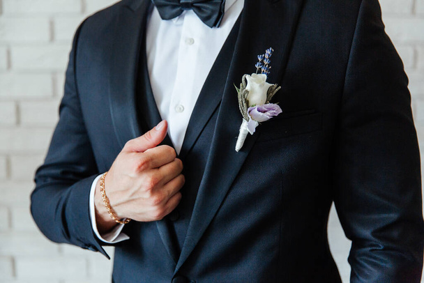 the groom in a black wedding suit, a tuxedo in a white shirt and a buttonhole - Foto, immagini