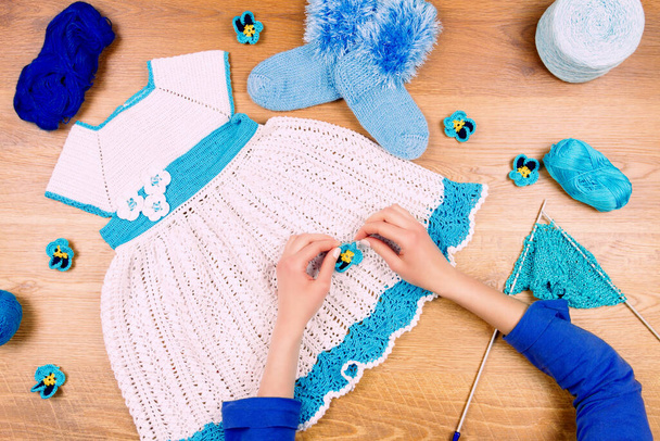 Kleermaker werkplek. vrouw breien op houten achtergrond het maken van blauwe jurk voor baby meisjes - Foto, afbeelding