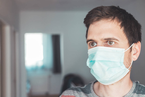 Young man indoor wearing a face mask, portrait. Corona and flu season. - Foto, Imagen
