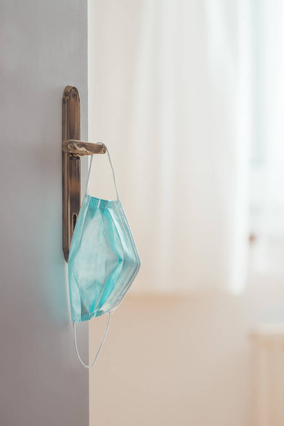 Face mask or surgical mask is hanging on a door handle  - Fotoğraf, Görsel