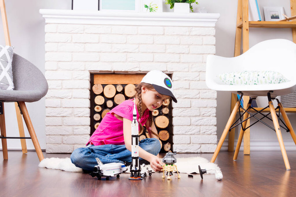 Kleine Kindermädchen spielen mit Kosmos-Spielzeughersteller: Rakete, Shuttle, Rover, Satellit und Astronautenpuppe in komfortablem Interieur zu Hause auf Holzboden - Foto, Bild