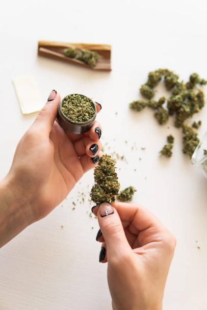 Close up of marijuana blunt with grinder. Woman rolling a cannabis blunt on white background. marijuana use concept. Woman preparing and rolling marijuana cannabis joint. - Foto, Imagen