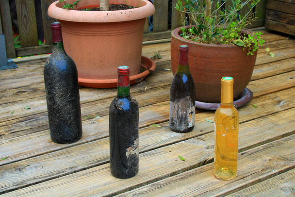 Zbliżenie na stare butelki zakurzonego wina. Zestaw różnych alkoholi z czarno-białych winogron. - Zdjęcie, obraz
