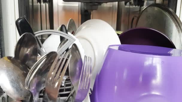 Kotitalouden nykyaikaisen astianpesukoneen avulla kotiäidin kädet ottavat puhtaat astiat astianpesukoneesta, lähikuva. Nykyaikaiset kodinkoneet kotona. 4K-video
 - Materiaali, video