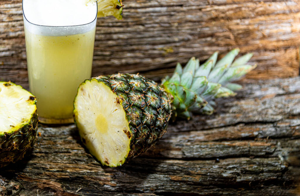 Pineapple. Tropical fruits. On a wooden background. Front view. Glass of juice. Refreshment. Detox diet. Morning feeding. Intestinal regulation. Body's health. Fitness food. Pineapple juice - Foto, afbeelding