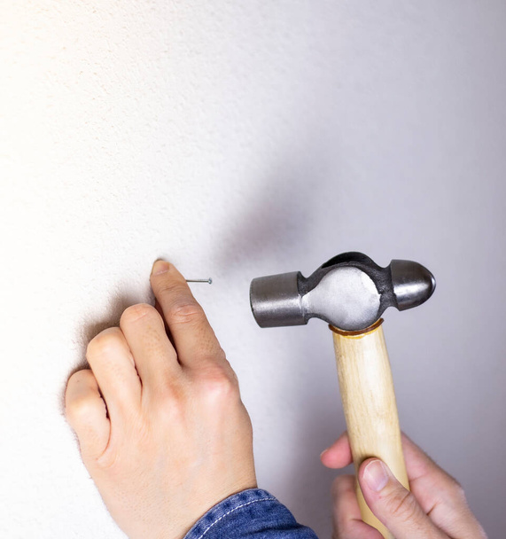 man driving a nail into the wall with a hammer - 写真・画像