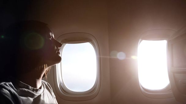 woman half-face silhouette against airliner windows closeup - Foto, Bild