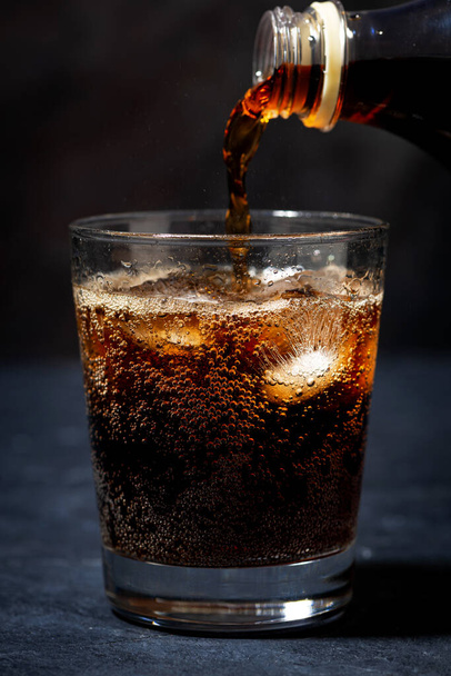Coca Cola is pouring into a glass from a bottle, vertical - Foto, Imagem
