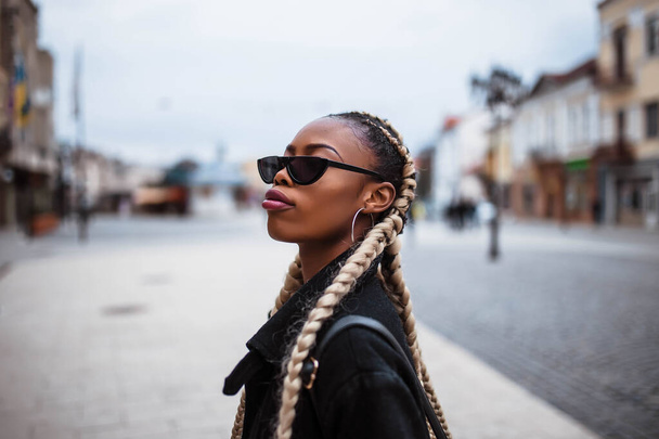 Portrait of african girl in the city. Black girl. Portrait in the city center. Girl wears glasses. - Photo, Image
