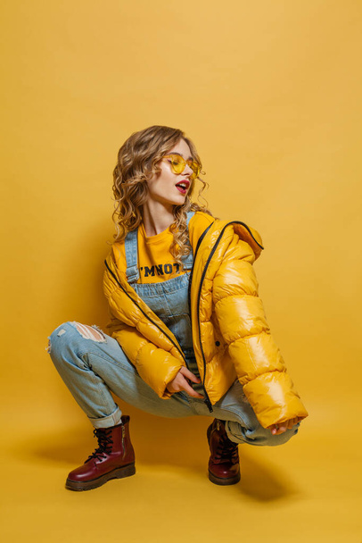Fashionable model girl in yellow winter jacket on bright yellow background - Photo, Image