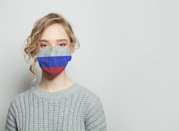 Młoda kobieta w masce z flagą. Koncepcja epidemii grypy i ochrony przed wirusami - Zdjęcie, obraz