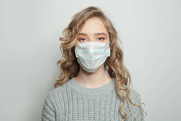 Krásná žena v masce obličeje na bílém pozadí. Žena v lékařské masce. Epidemie chřipky a koncepce ochrany proti virům - Fotografie, Obrázek