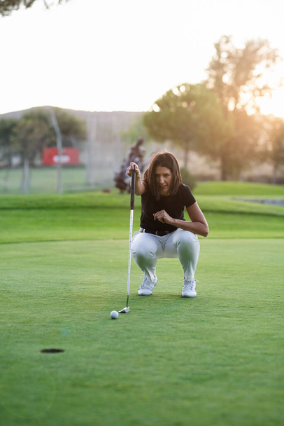 Mulher golfista linha de verificação para colocar bola de golfe no verde
 - Foto, Imagem