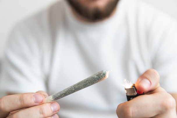 Hombre fumando hierba en el interior. Fumar marihuana en casa. Uso recreativo del cannabis. De cerca.
 . - Foto, imagen