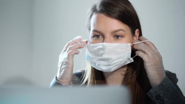 Young woman working at laptop computer in office mask during epidemic covid-19 - Záběry, video