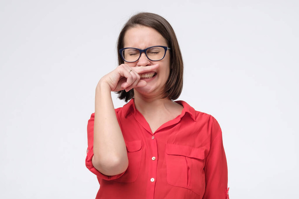 Зрелая белая женщина в очках закрывает нос рукой, изолированной на белой стене
 - Фото, изображение