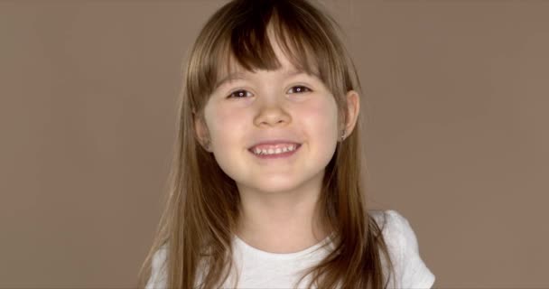 Portrait of a little cute 7 year old girl in a white tshirt, posing and smiling - Footage, Video