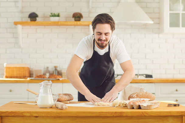 Baker male bearded man makes fresh bread dough at a table in the bakery kitchen. - Fotografie, Obrázek