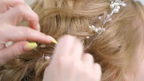 Fastening the hair with tiaras, a make-up master attaches a caron of branches to the hairstyle. Beauty industry, hair care, preparation for the celebration. - Footage, Video
