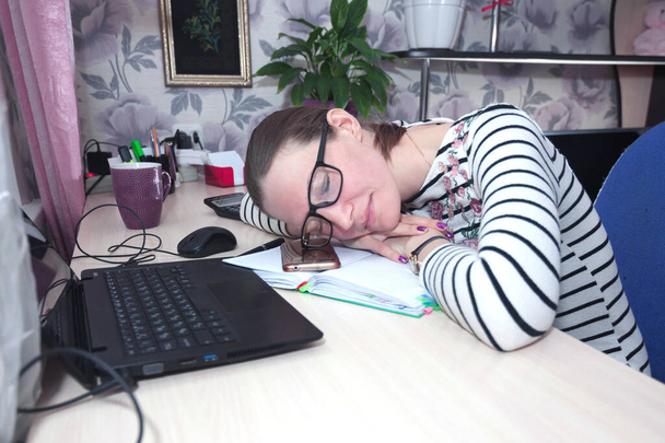 Jeune femme à lunettes, restée à la maison, fatiguée du travail et endormie. Communication à distance et travail en ligne
 - Photo, image