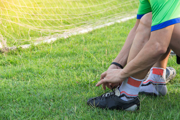 Jeune athlète asiatique homme attachant des chaussures de football à côté du terrain, football masculin prêt à jouer sur le terrain, concept de bien-être et de sport
 - Photo, image
