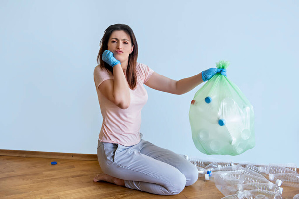 The girl puts empty plastic bottles in a bag. Sorting and recycling will preserve the nature of the land. Sort is not difficult. - Foto, afbeelding