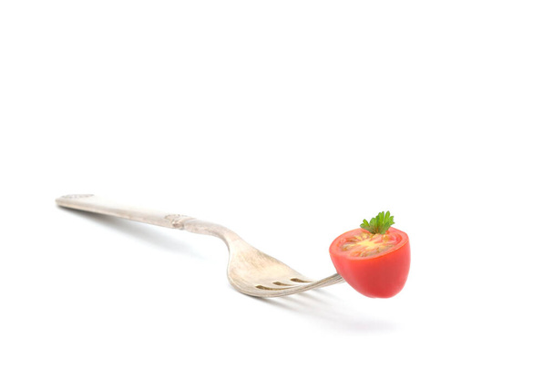 Pomidor wiśniowy przecięty na pół i nadziany na zęby widelca vintahe sfotografowany na białym tle z dużą ilością miejsca do kopiowania. - Zdjęcie, obraz
