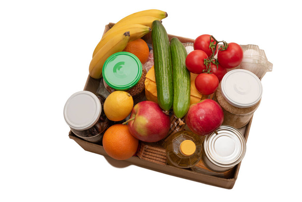 Ruoan lahjoituslaatikko eristetty valkoisella. Avaa pahvilaatikko öljyllä, säilykkeillä, viljalla, vihanneksilla, hedelmillä. Hyväntekeväisyyslahjoituksia apua tarvitseville. Turvallinen toimitus karanteenin aikana. Yläkuva
 - Valokuva, kuva