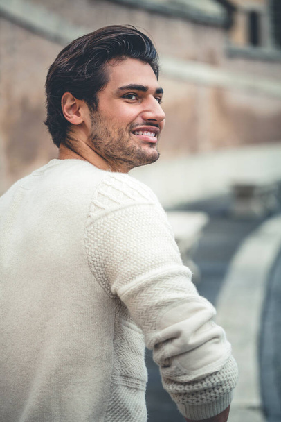 Handsome young man laughing outdoor. Stylish hairstyle, stubble. In the street in the city. From the back. - Foto, imagen