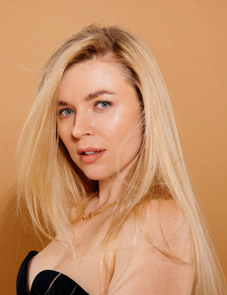 close up portrait of beautiful blonde woman posing in studio against nude background - Foto, imagen