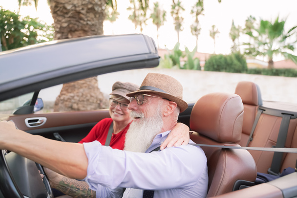 ロマンチックな瞬間にコンバーチブル車の中のカップル-休暇中にロードトリップを楽しんで退職したカップル-旅行、ファッション、楽しい高齢者のコンセプト-人間の顔に焦点を当てる - 写真・画像